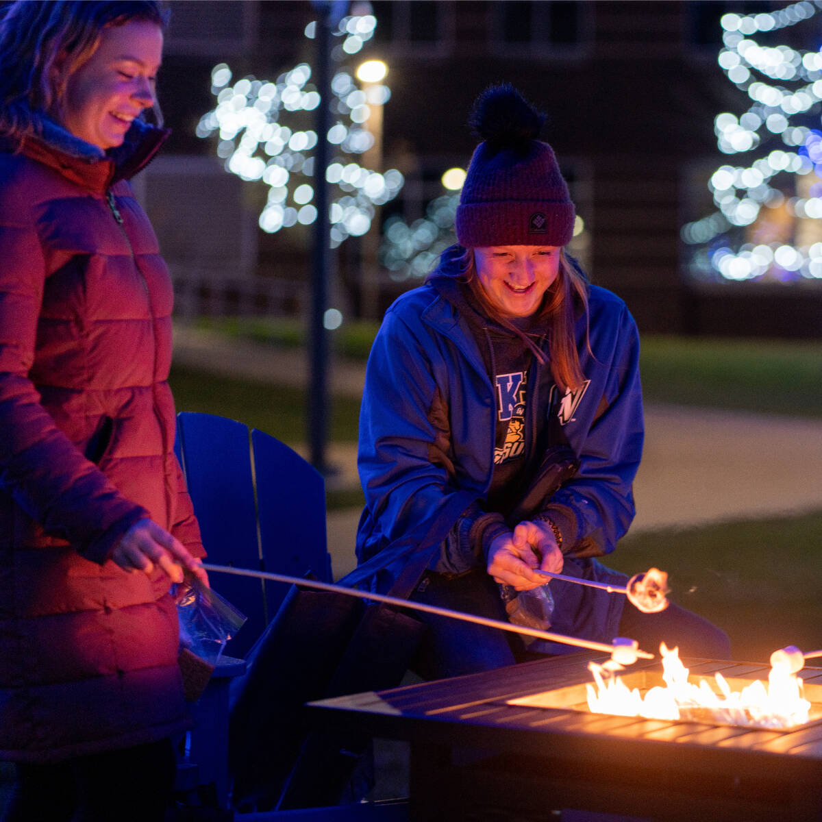 Two students roasting marshmallows over a fire